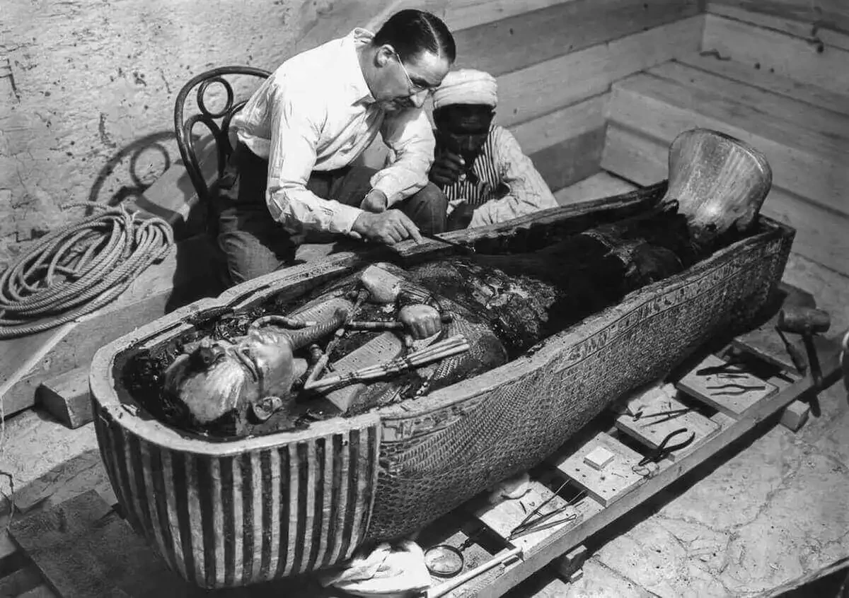 Howard Carter observing the coffin still covered in “black pitch-like mass”. Harry Burton, The Griffith Institute, Oxford.